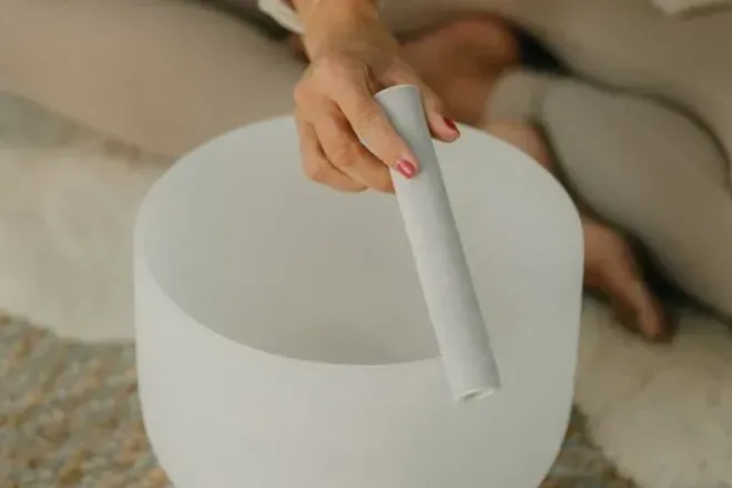 Une main fait chanter un bol de quartz givré