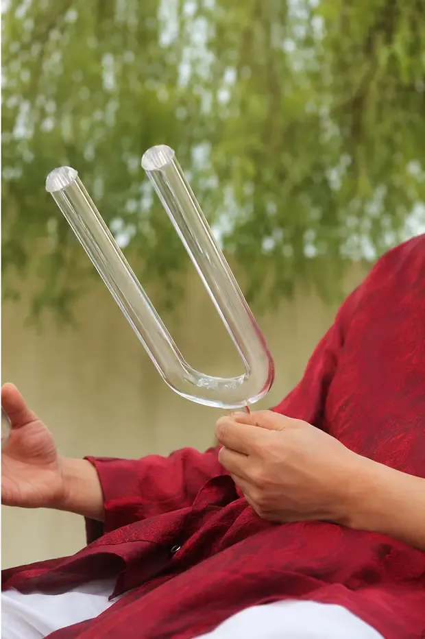 Un diapason en cristal de quartz transparent, tenu en main