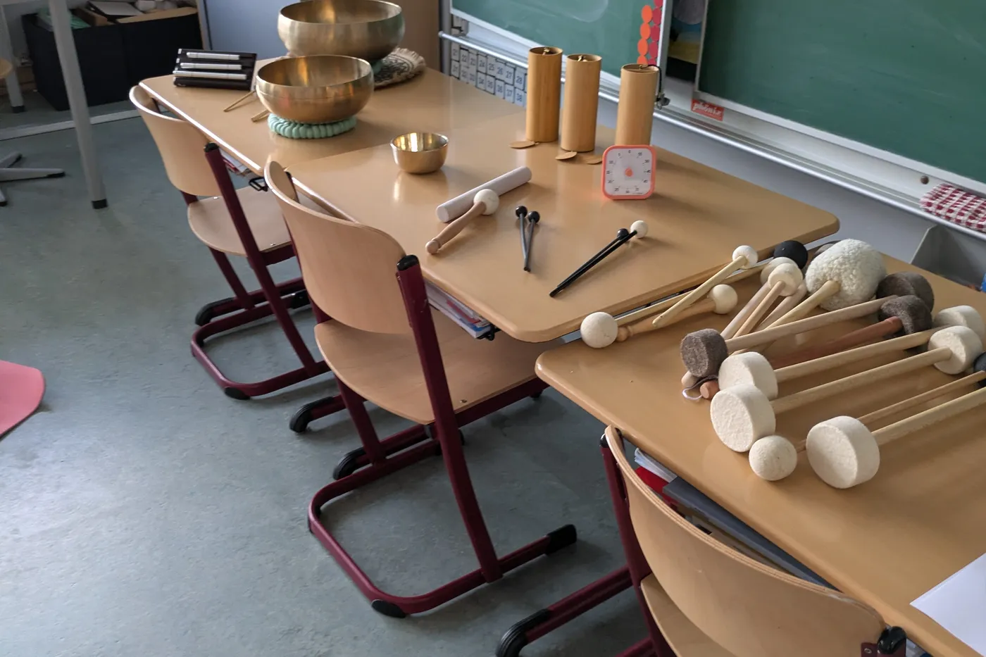 Les bols et leurs maillets préparés sur une table, devant le tableau de la classe.
