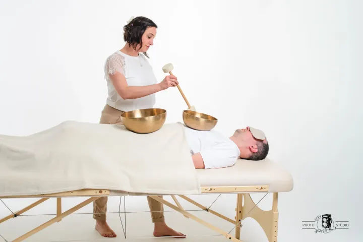 Des bols chantants posés sur le corps, pendant un massage sonore